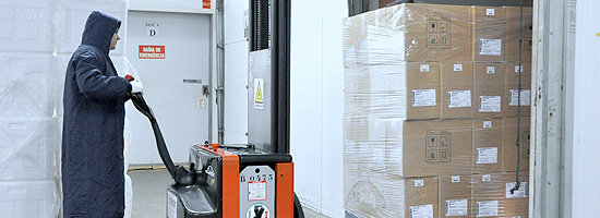 Colaborador de Bio-Manguinhos/Fiocruz operando empilhadeira e posicionando caixas no caminhão baú