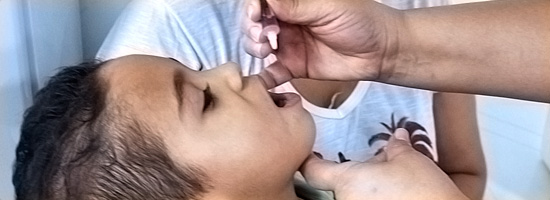 Criança com a boca aberta, recebendo dose da vacina poliomielite oral