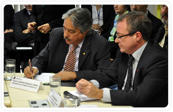 O presidente da Fiocruz, Paulo Gadelha, assina o acordo, observado pelo secretário Carlos Gadelha
